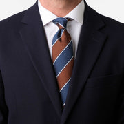 Cravatta regimental blu e marrone indossata con camicia bianca e giacca scura