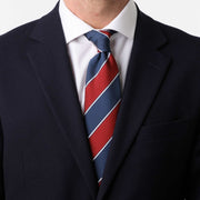Cravatta regimental blu navy e rossa indossata con camicia bianca e giacca scura