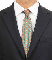 Cravatta marrone con fantasia geometrica celeste indossata con camicia bianca e giacca scura